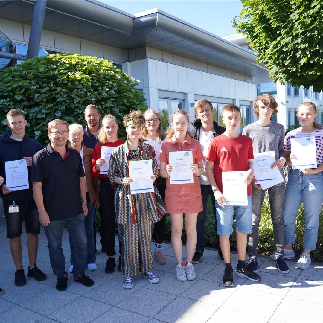 Personen posieren mit Urkunden vor einem Gebäude