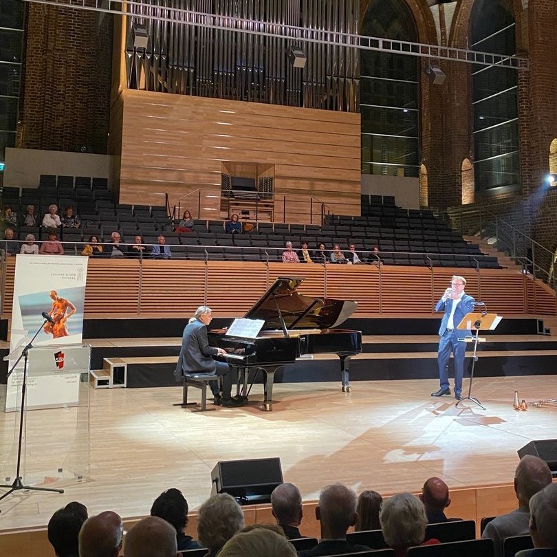 eine Person spielt Klavier, während eine zweite Trompete spielt,