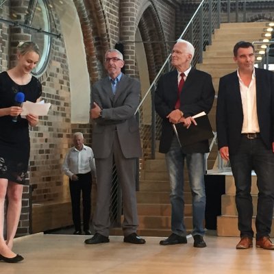 Mehrere männliche und eine weibliche Person stehen auf einer Bühne