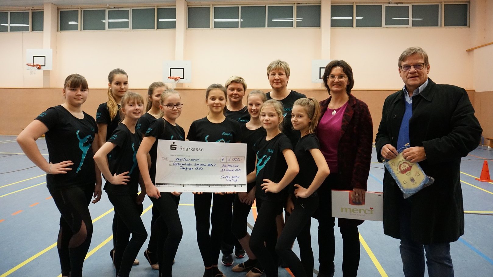 Übergabe Förderung Turnen, mehrere Kinder und ein Paar Erwachsene stehen als Gruppe zusammen