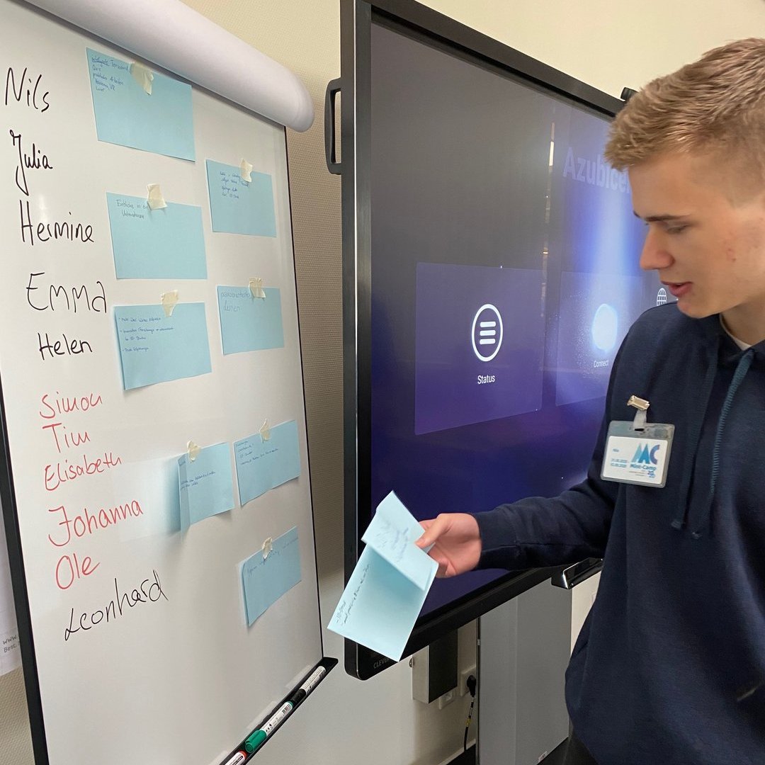 eine Person nimmt etwas von einem Whiteboard auf dem etwas geschrieben steht