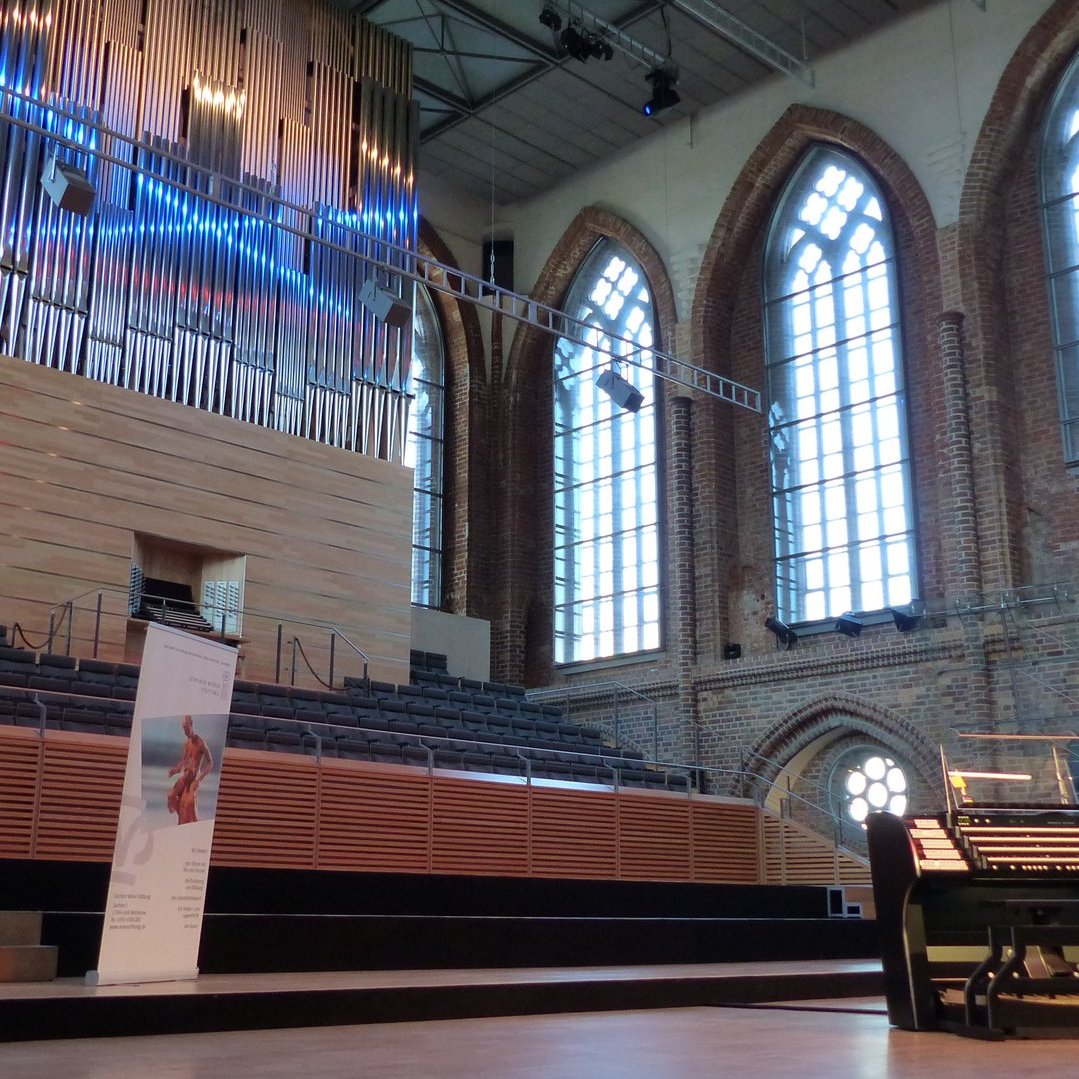 Zu sehen ist eine Orgelkirche mit einem Podium und Sitzbänken